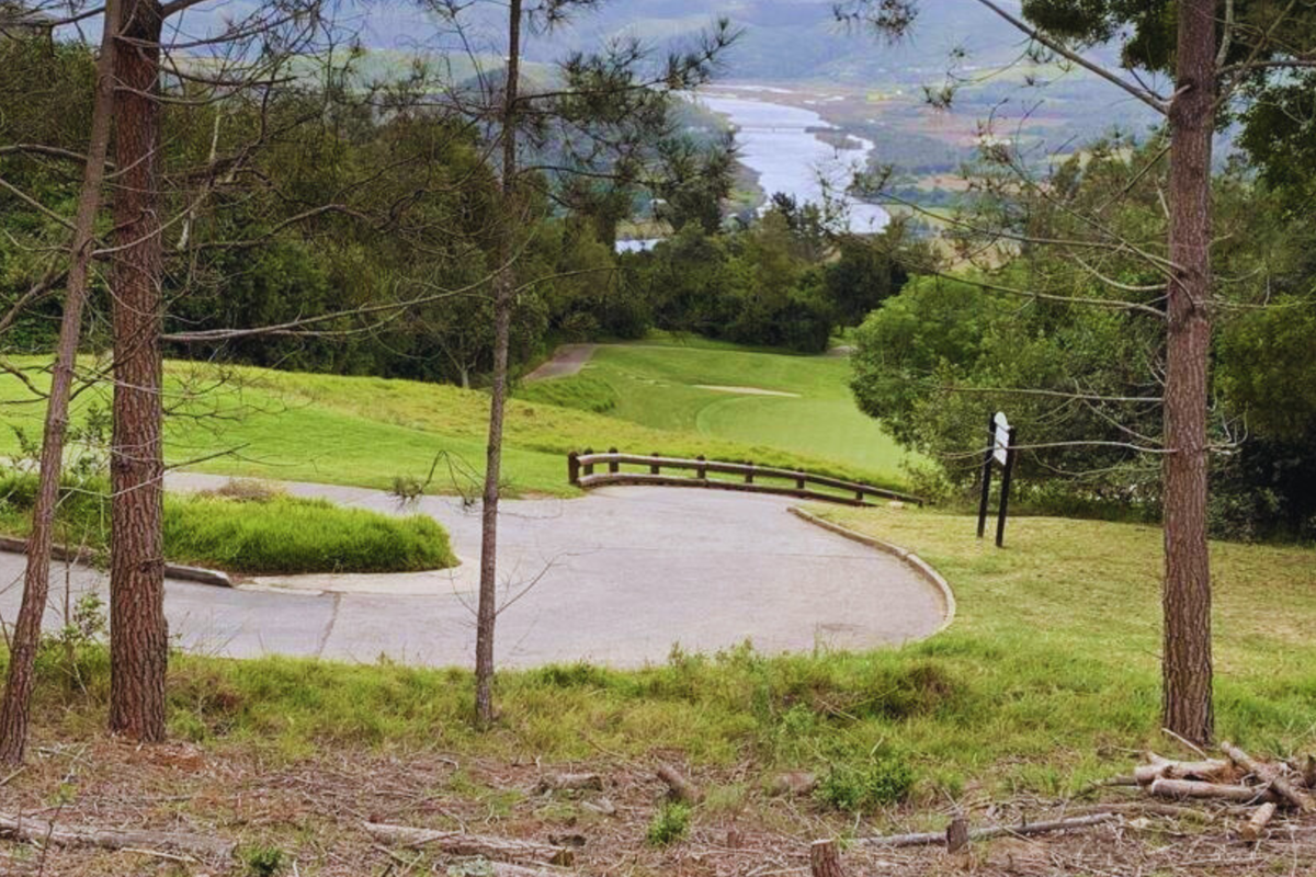 Scenic elevated view overlooking a paved driveway, landscaped grounds, and a distant river landscape.