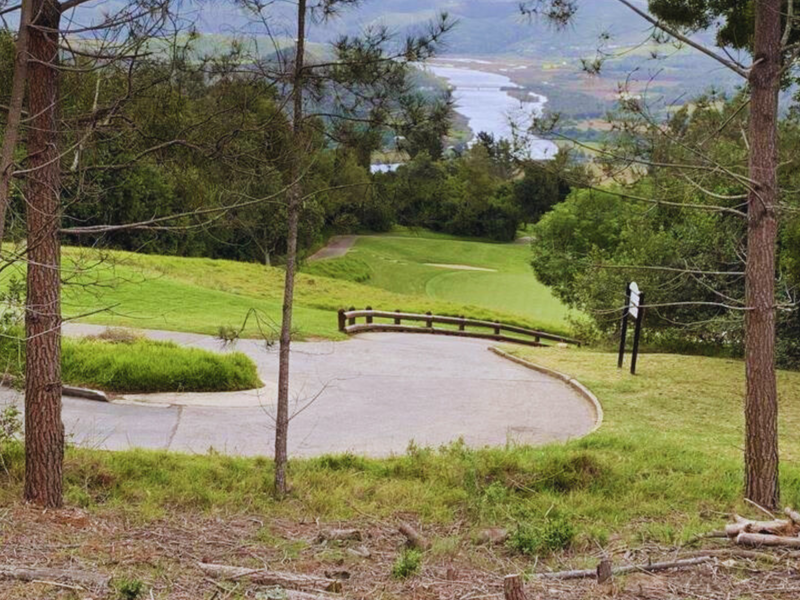Scenic elevated view overlooking a paved driveway, landscaped grounds, and a distant river landscape.