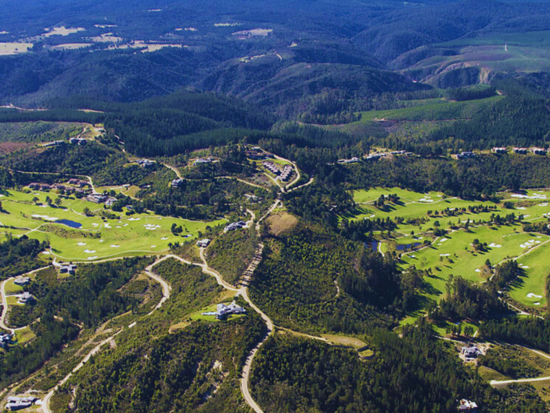 An expansive aerial view of a residential golf estate, showcasing the layout of the course, surrounding landscape, and integrated property plots.