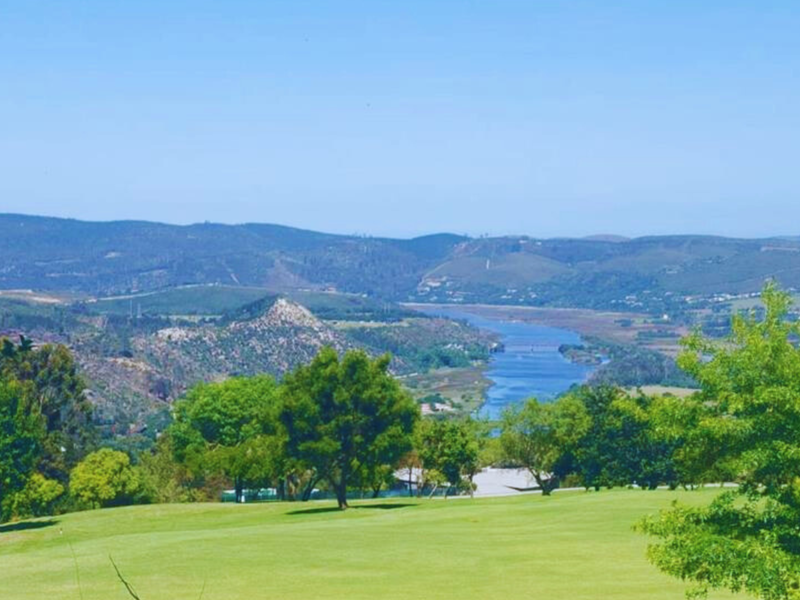 A scenic landscape view overlooking a river, rolling hills, and lush greenery, showcasing the natural beauty of the surrounding area.