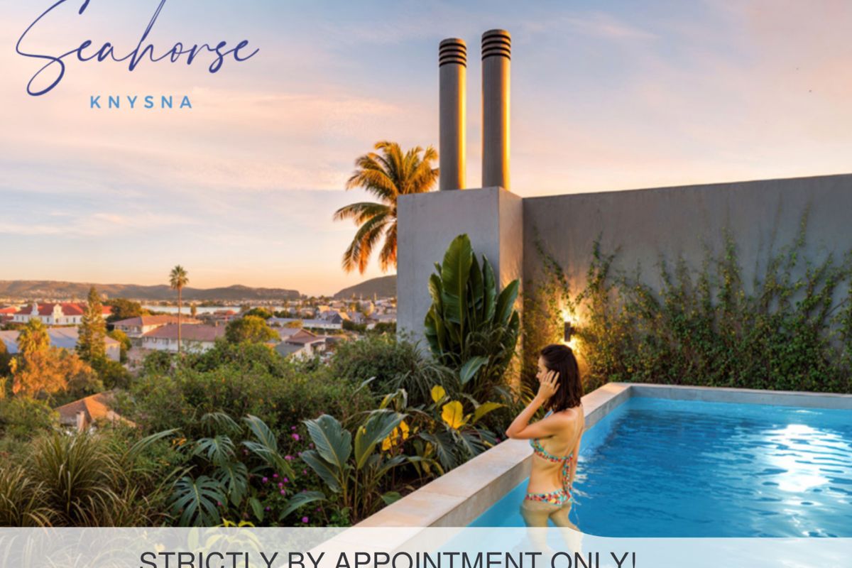 An elevated swimming pool area featuring modern chimney stacks and panoramic views of the surrounding landscape at sunset.