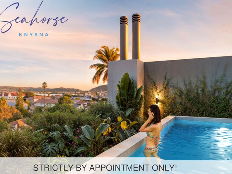 An elevated swimming pool area featuring modern chimney stacks and panoramic views of the surrounding landscape at sunset.