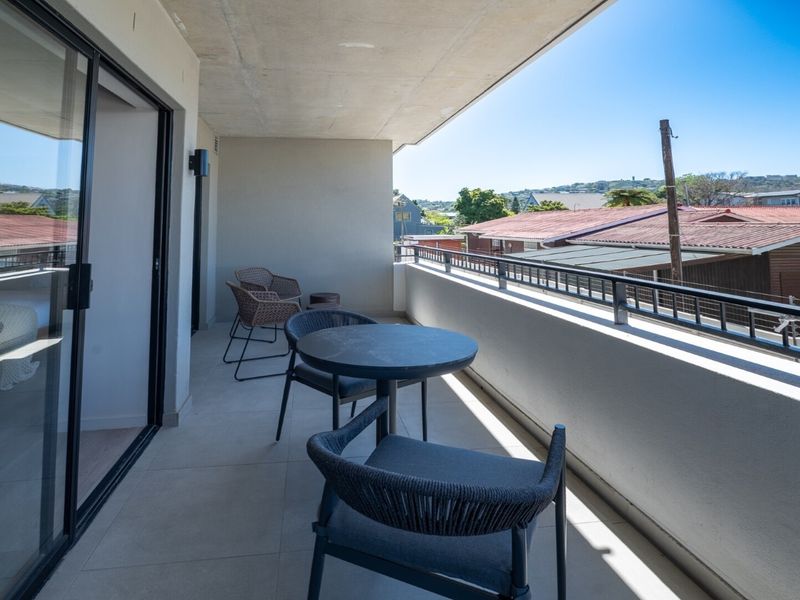 A spacious covered balcony featuring tiled flooring, a metal balustrade, and large sliding glass doors providing access to the interior.