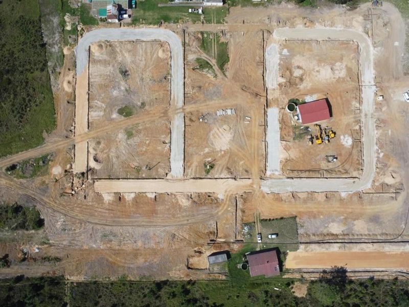Aerial view of a residential development site showing ongoing earthworks, road layout, and initial infrastructure preparation on vacant land.