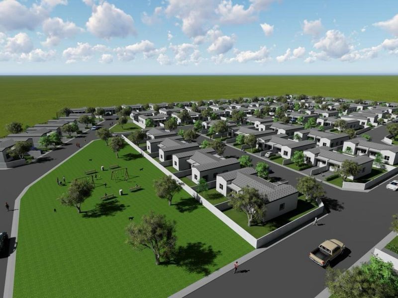 An aerial perspective of a residential development featuring multiple housing units, paved street infrastructure, and a central landscaped park area.