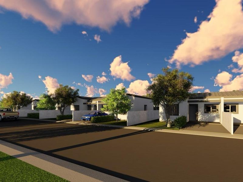 A street-level view of a residential development featuring modern single-story homes with boundary walls and paved access roads.