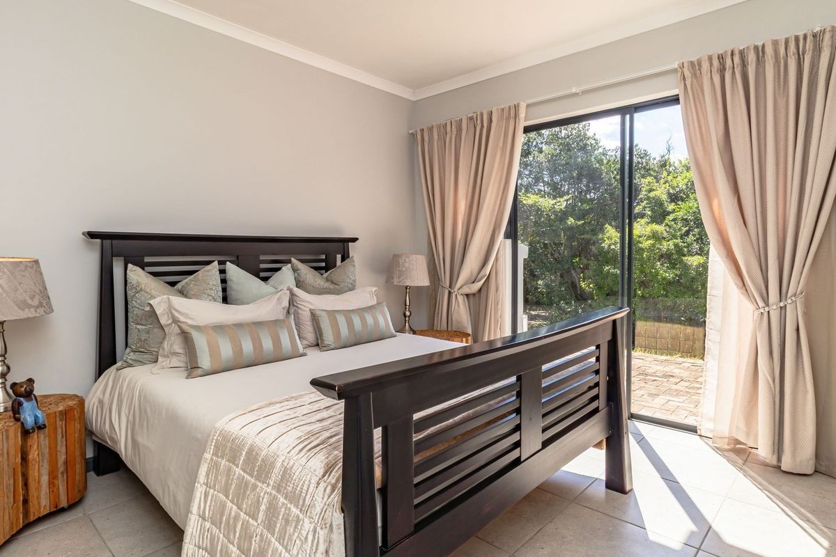 A well-maintained bedroom featuring tiled flooring and a large sliding glass door providing direct access to the outdoor patio area.