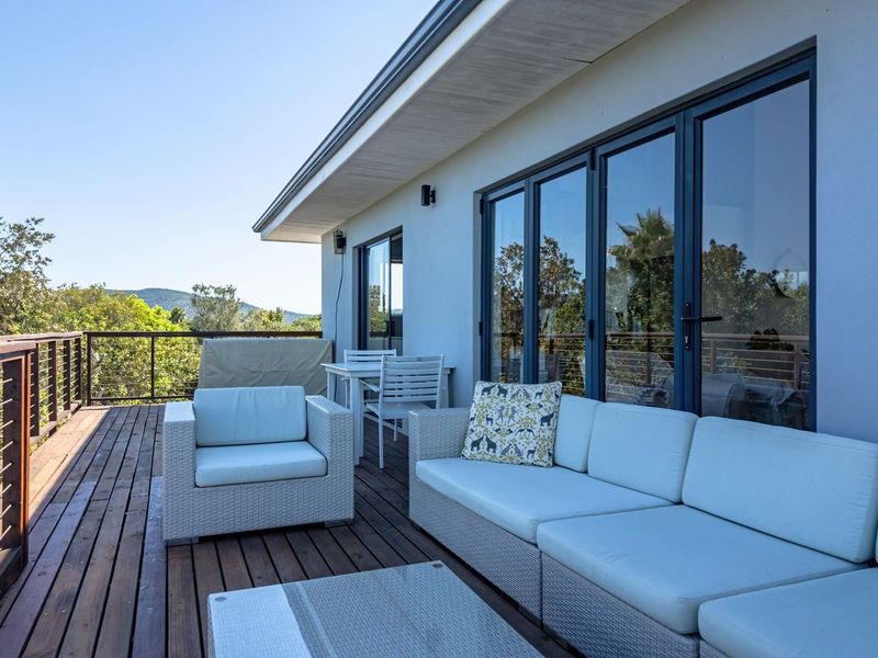 Spacious elevated timber deck balcony featuring modern aluminium folding doors and metal balustrades, offering an expansive outdoor living area with scenic views.