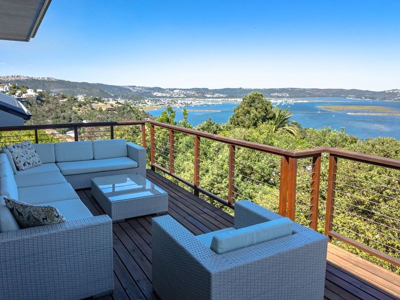 Spacious elevated balcony featuring timber decking and a wire balustrade, offering expansive panoramic views of the estuary and surrounding landscape.