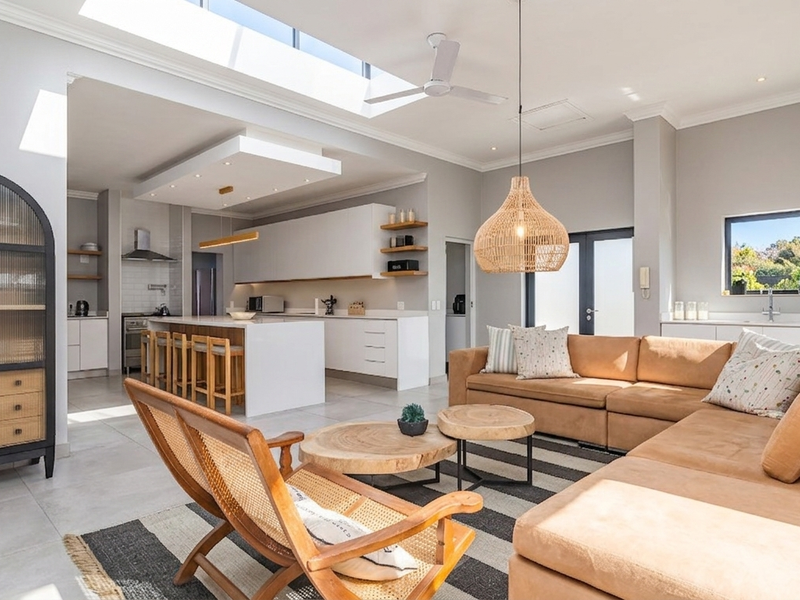 Spacious open-plan living area featuring a modern kitchen with a central island, skylight, and seamless flow to the lounge space.