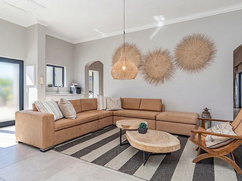 Spacious living room featuring neutral tiled flooring, an elegant archway, and double glass doors providing natural light and access to the outdoor area.