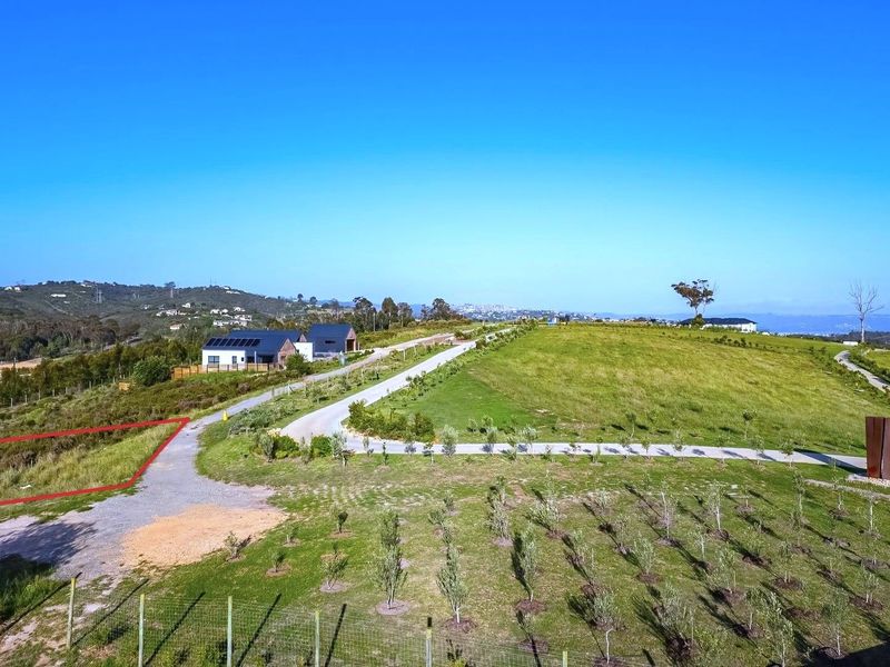 An aerial view of a residential vacant land plot featuring established landscaping, paved access roads, and surrounding estate infrastructure.