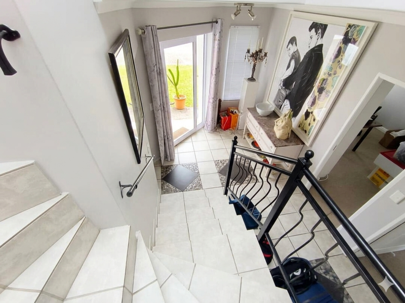 An inviting entryway featuring a tiled staircase with a wrought iron balustrade, leading to a glass-panelled door with direct garden access.