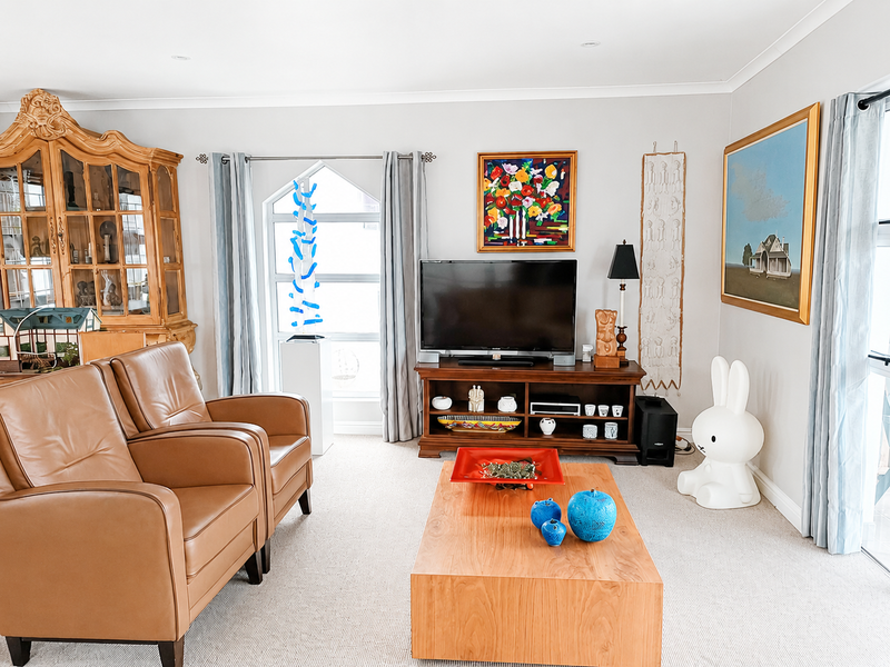 A bright and well-maintained living room featuring neutral carpeting, recessed downlighting, and a large feature window that allows for ample natural light.