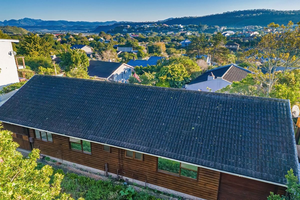 Aerial view of a residential property featuring a tiled roof, timber cladding, and an elevated timber deck overlooking the surrounding neighbourhood.