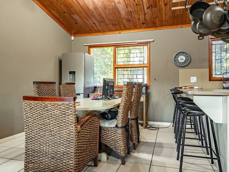 Open-plan kitchen and dining area featuring a timber-clad vaulted ceiling, tiled flooring, and a functional breakfast bar with integrated seating.