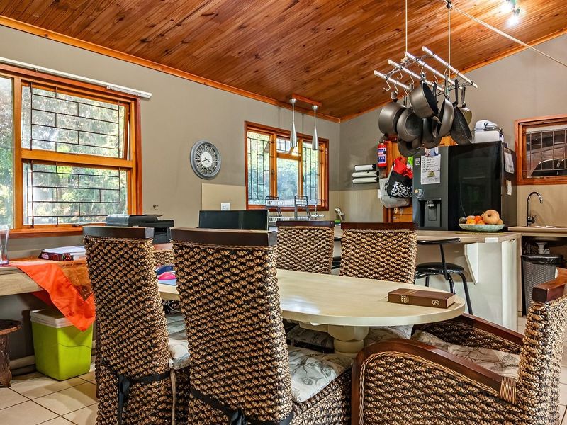 Open-plan kitchen and dining area featuring a timber ceiling, tiled floors, and functional built-in cabinetry with integrated appliances.