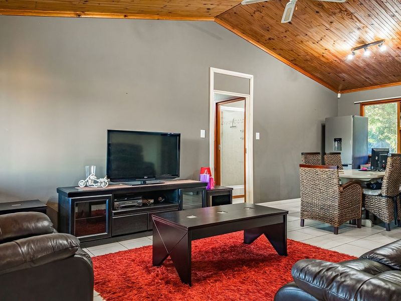 Spacious living area featuring a vaulted timber ceiling, tiled flooring, and a ceiling fan, creating a comfortable and open atmosphere.