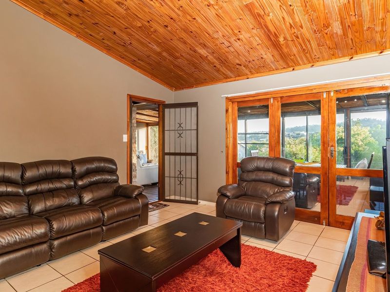 Spacious living room featuring a vaulted timber ceiling, tiled flooring, and large timber-framed glass doors providing access to the outdoor area.