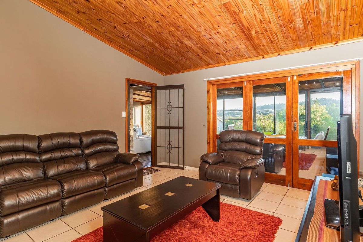 Spacious living room featuring a vaulted timber ceiling, tiled flooring, and large timber-framed glass doors providing access to the outdoor area.
