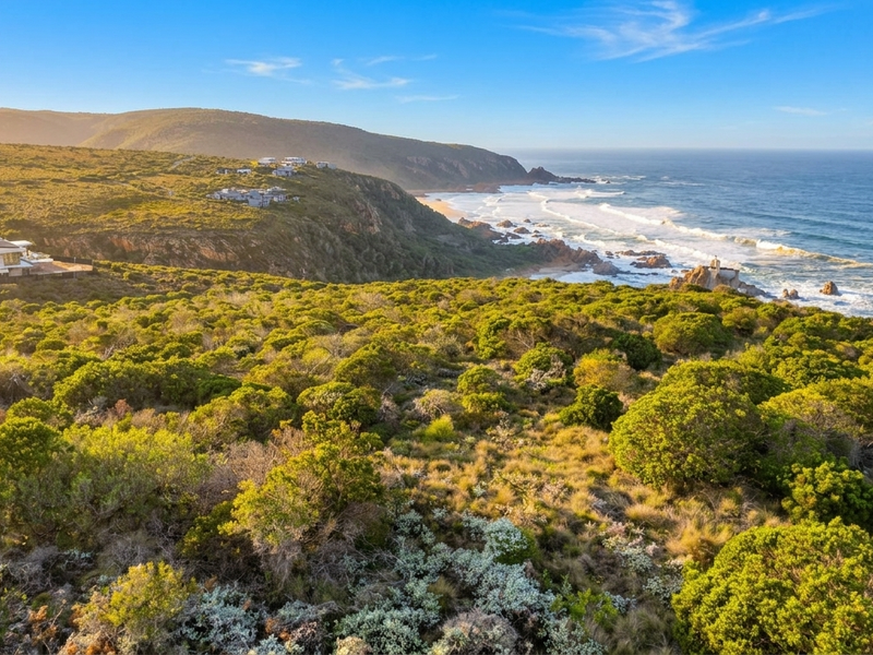 An aerial view of the coastal residential land, showcasing the natural landscape, surrounding vegetation, and proximity to the ocean.