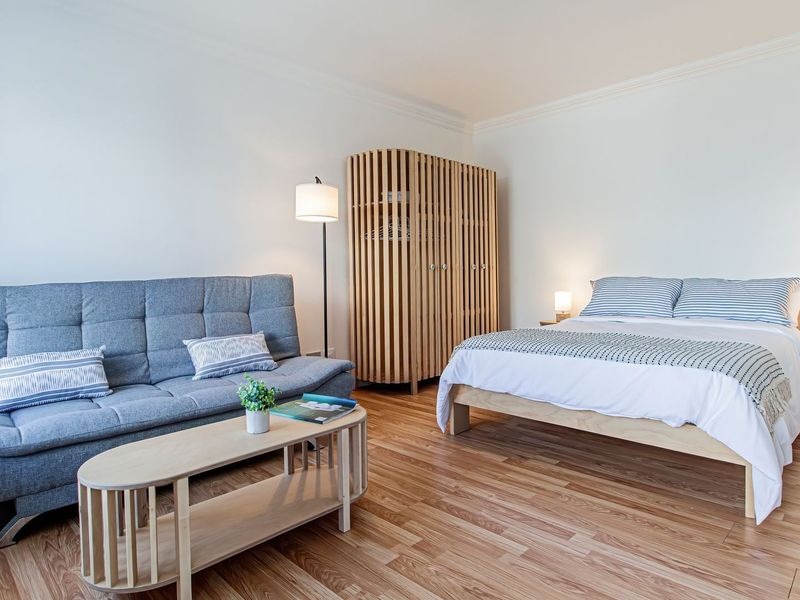 A well-maintained bedroom featuring light wood-look laminate flooring and classic crown molding, offering a clean and neutral living space.