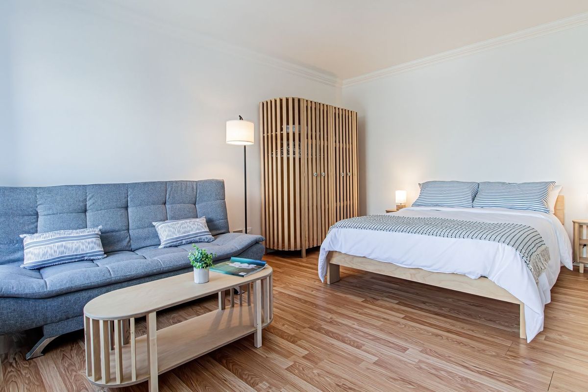 A well-maintained bedroom featuring light wood-look laminate flooring and classic crown molding, offering a clean and neutral living space.