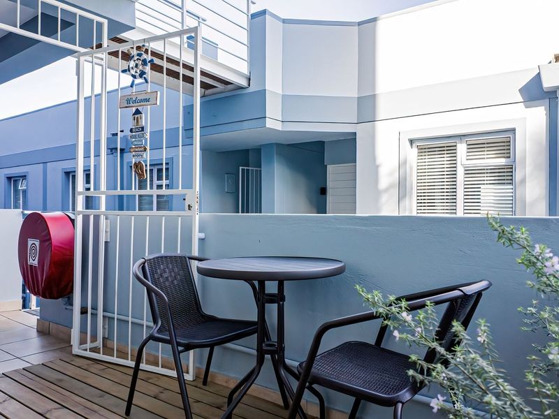 A well-maintained balcony area featuring a combination of tiled and wooden decking, secured by a metal gate, providing a functional outdoor space.