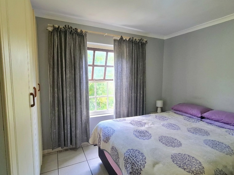 A bedroom featuring tiled flooring, a built-in wardrobe, and a window with natural light.