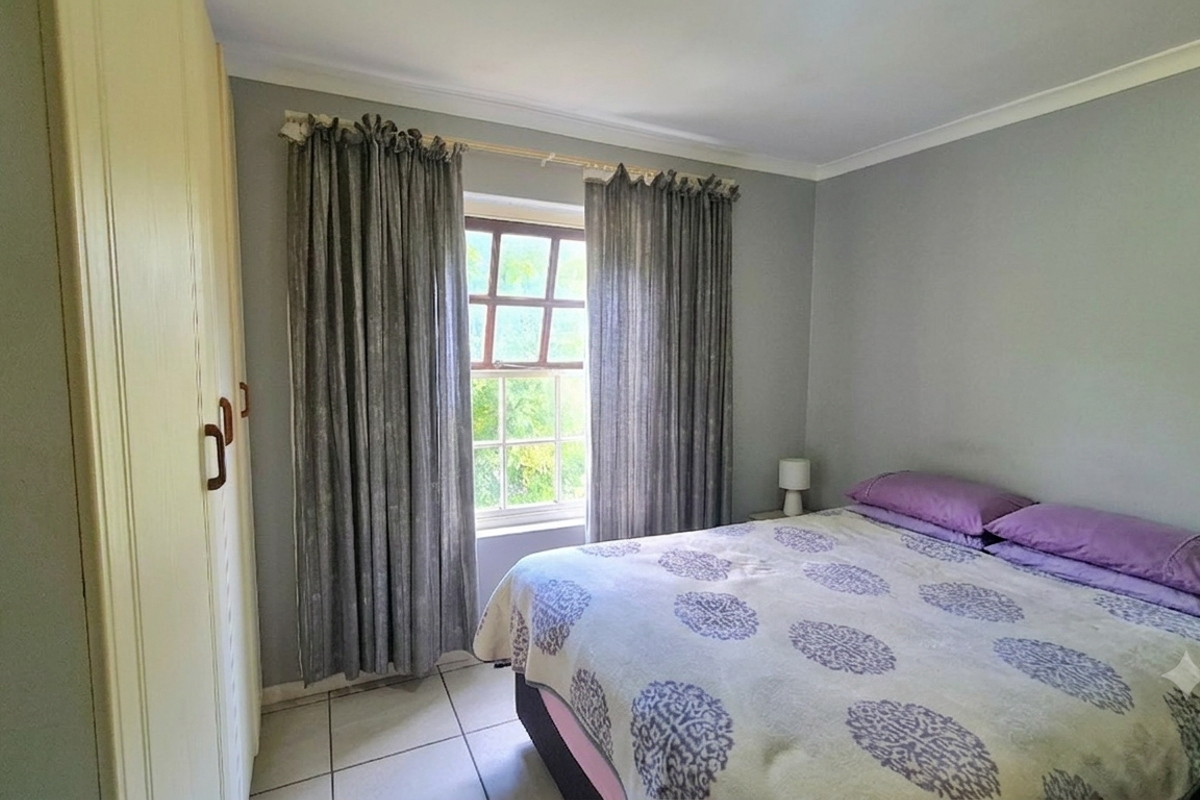 A bedroom featuring tiled flooring, a built-in wardrobe, and a window with natural light.