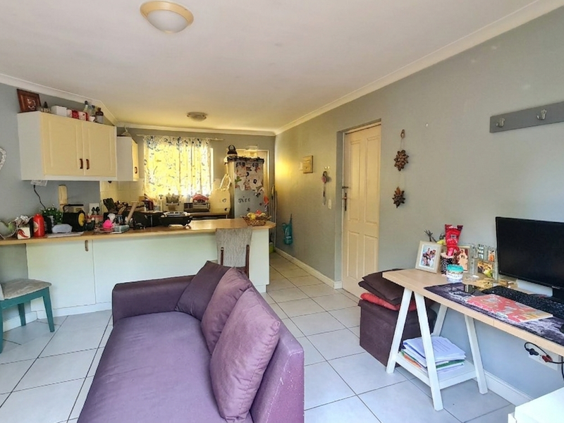 Open-plan living area featuring tiled flooring, a functional kitchen with breakfast bar, and neutral wall tones, providing a versatile space for living and dining.