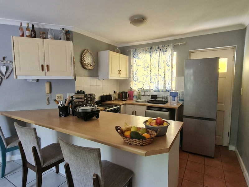 A functional kitchen featuring built-in cabinetry, a breakfast bar, tiled backsplash, and a stainless steel sink, providing a practical layout for daily use.
