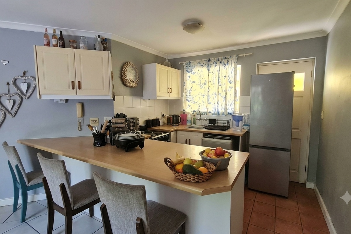 A functional kitchen featuring built-in cabinetry, a breakfast bar, tiled backsplash, and a stainless steel sink, providing a practical layout for daily use.