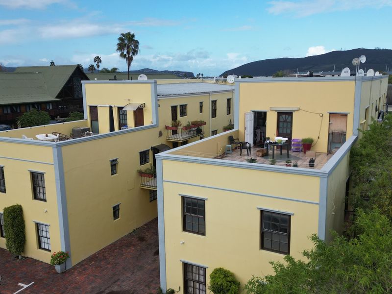 Aerial view of a multi-story apartment complex featuring yellow facades, flat roof terraces, and brick-paved courtyard areas.