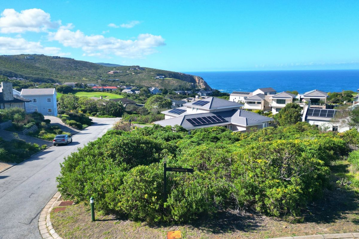 An aerial view of a coastal residential estate featuring paved roads, established vegetation, and scenic ocean views.