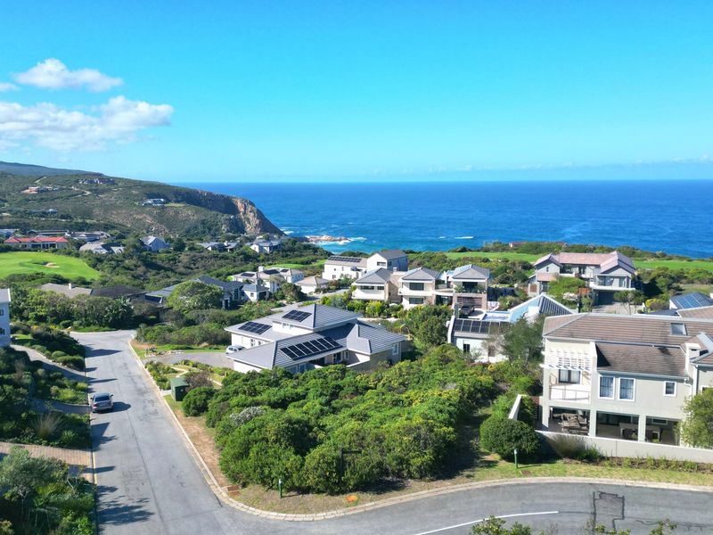 An elevated aerial view of a coastal residential estate featuring paved roads, landscaped surroundings, and proximity to the ocean.
