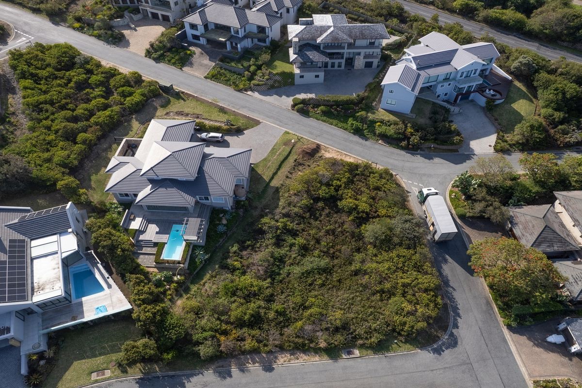 Aerial view of a vacant residential plot situated within a developed estate, featuring established road access and surrounding luxury homes.