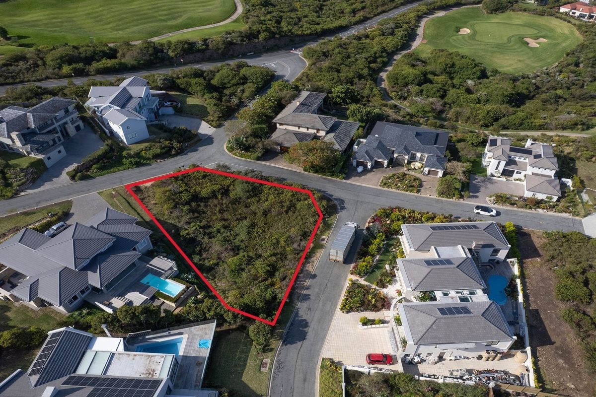 Aerial view of a vacant residential plot situated within a developed estate, featuring road access and surrounding established homes.