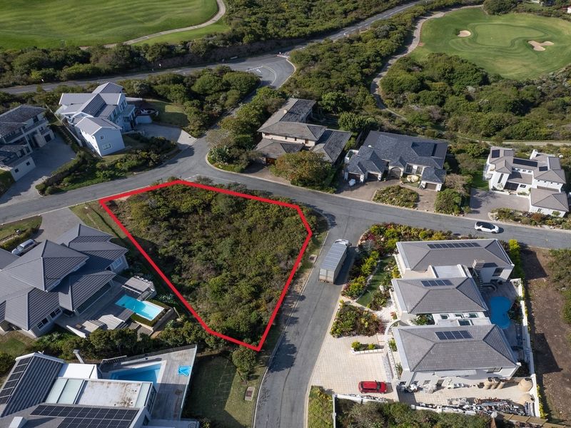Aerial view of a vacant residential plot situated within a developed estate, featuring road access and surrounding established homes.