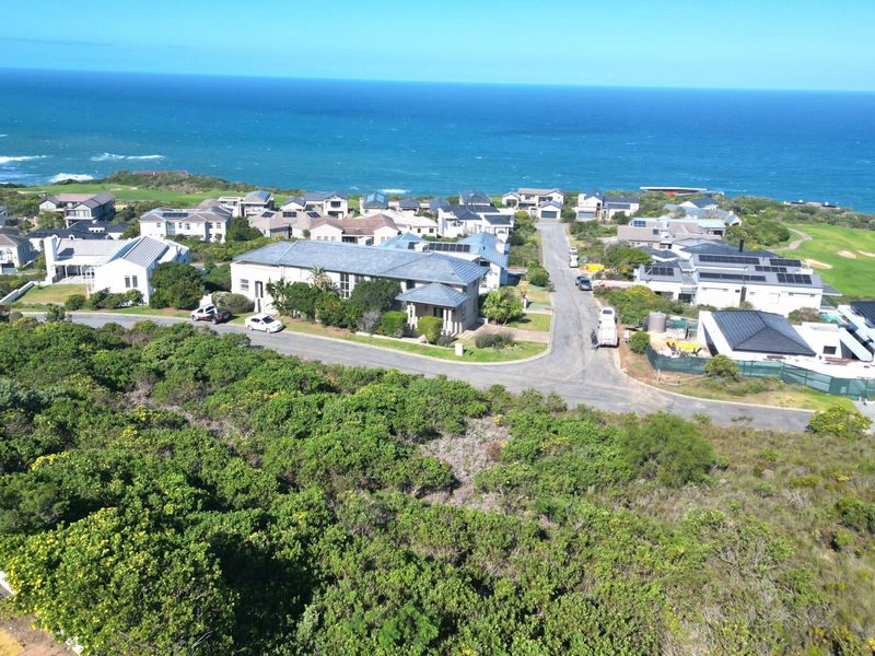 An aerial view of a coastal residential estate featuring paved roads, established homes, and proximity to the ocean and golf course.