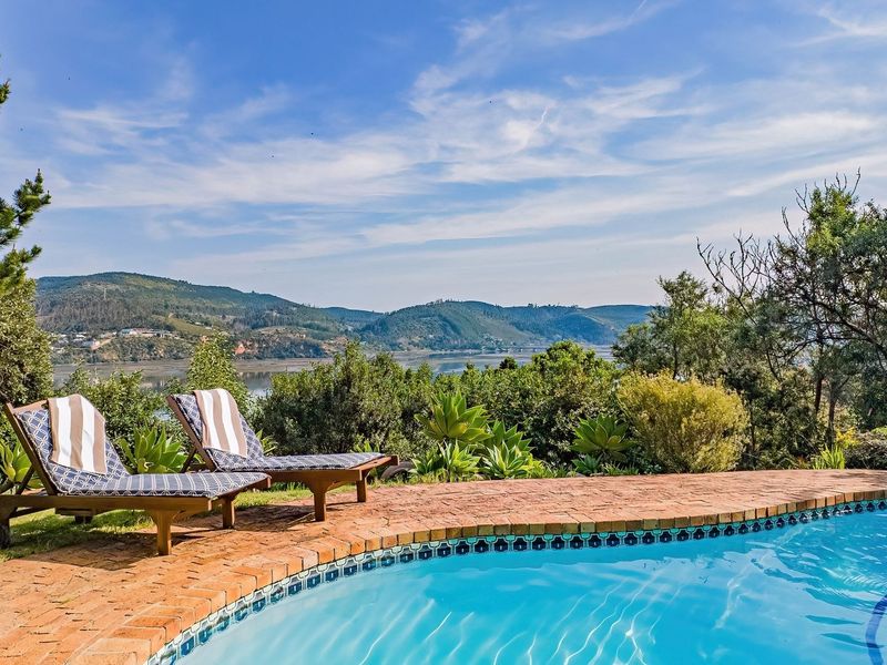 A scenic outdoor pool area featuring brick coping and a tiled edge, overlooking a beautiful landscape with mountain and water views.