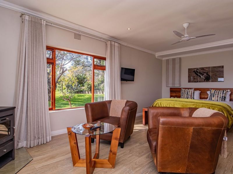 Spacious bedroom featuring a wood-burning stove, ceiling fan, and large windows overlooking the garden, finished with high-quality laminate flooring and crown molding.