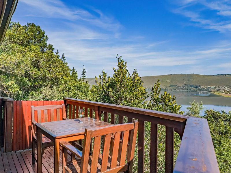 A wooden balcony featuring timber decking and railings, offering scenic views of the surrounding landscape and water.