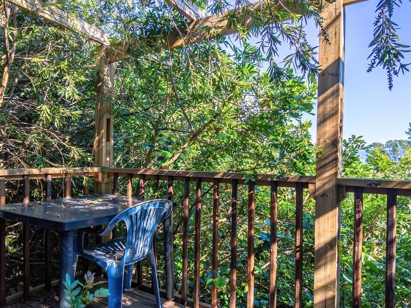 A rustic timber-framed balcony or deck area featuring a wooden balustrade, offering an elevated outdoor space surrounded by mature trees.