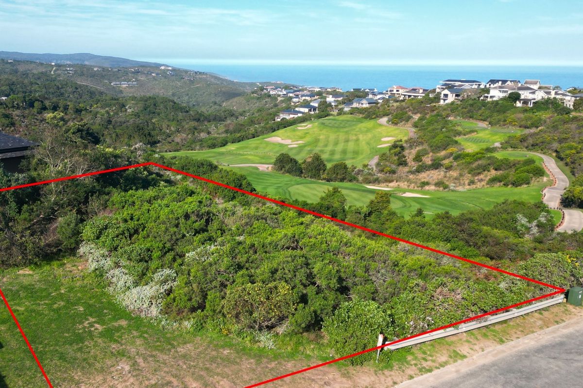 An aerial view of a vacant residential plot featuring natural vegetation, with scenic views of the surrounding golf course and coastline.