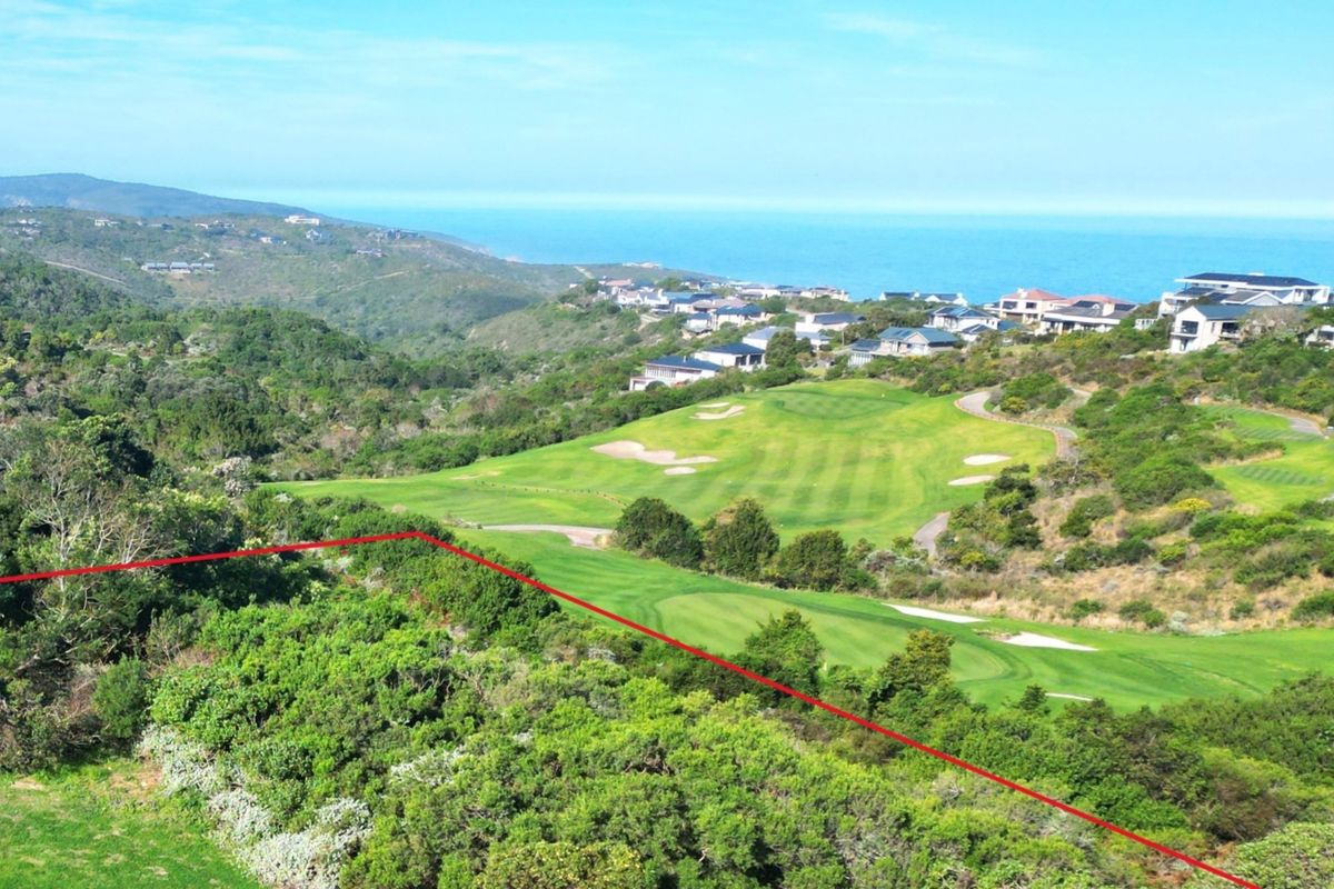 An elevated aerial view of a vacant residential plot overlooking a golf course and the ocean in the distance.