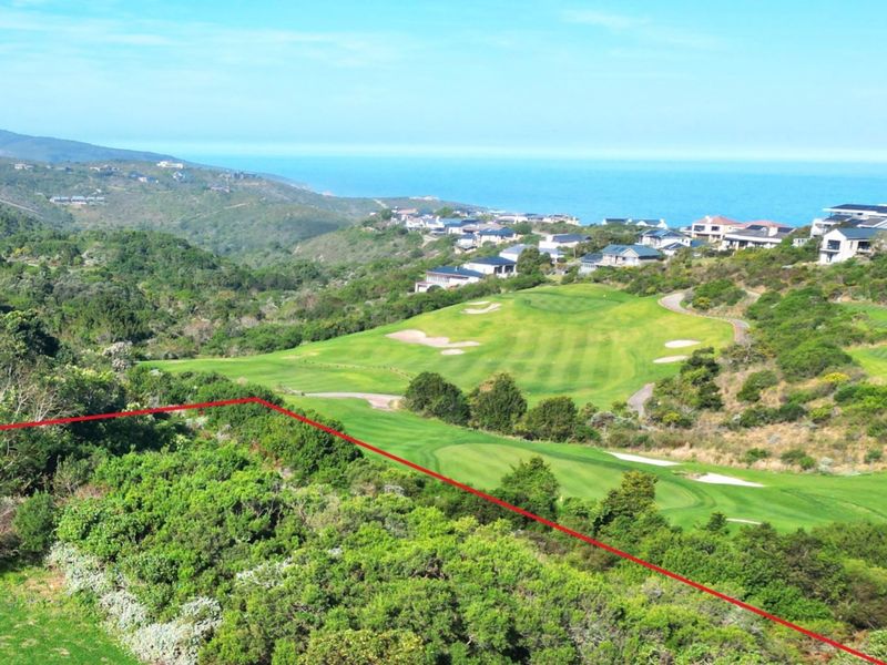 An elevated aerial view of a vacant residential plot overlooking a golf course and the ocean in the distance.