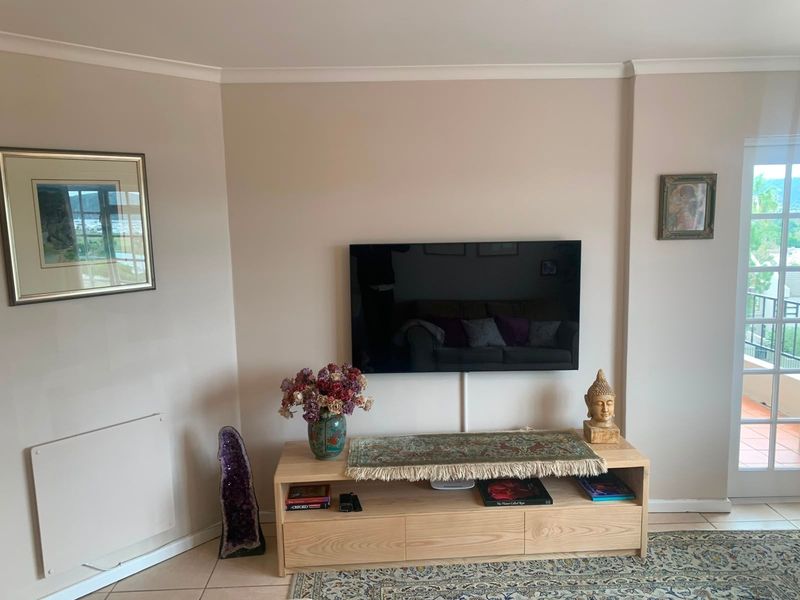 A well-maintained living room area featuring neutral wall tones, tiled flooring, and a glass panel door leading to an outdoor space.