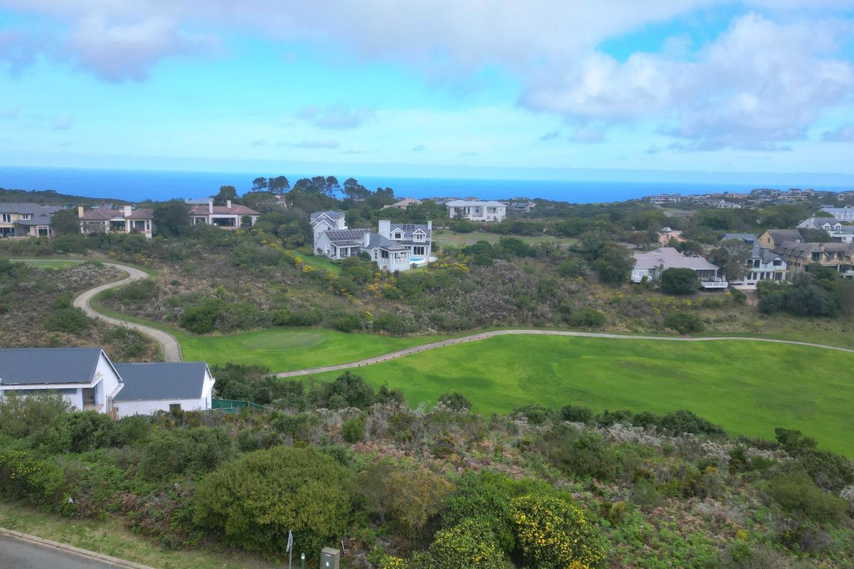 An elevated aerial view of a residential estate featuring a golf course and scenic coastal landscape.