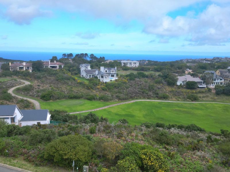 An elevated aerial view of a residential estate featuring a golf course and scenic coastal landscape.